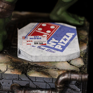 Close-up of the vintage NY Pizza box accessory and weathered sewer diorama base with drainage pipe on the Michelangelo statue.