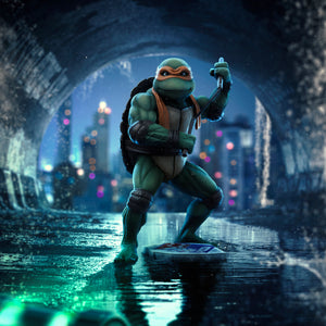 Composite artwork of the Iron Studios TMNT 1990 Michelangelo 1/10 scale statue standing in a flooded New York City sewer tunnel.