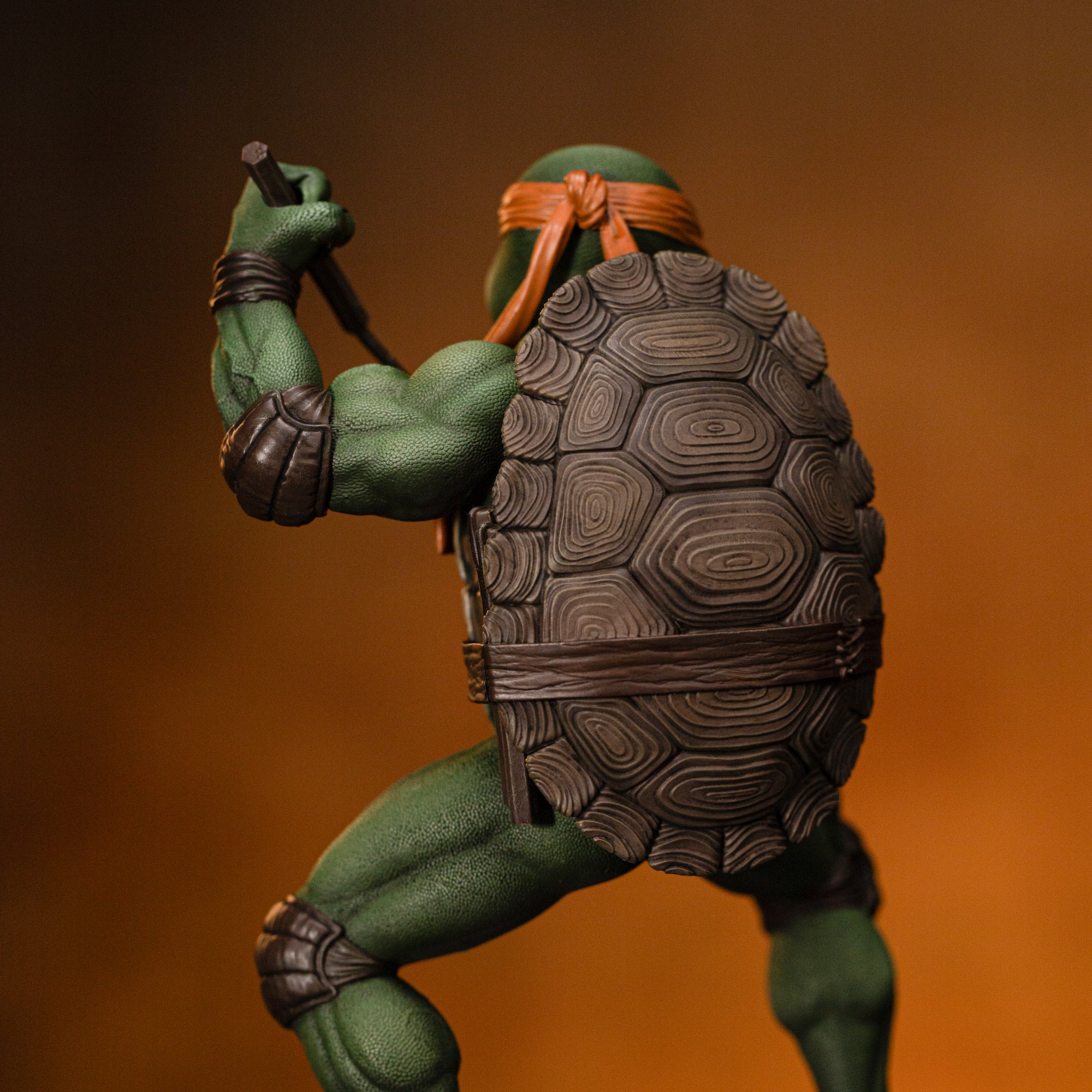 Rear close-up highlighting Michelangelo's sculpted carapace shell, brown belt, and knotted orange bandana on the Iron Studios statue.