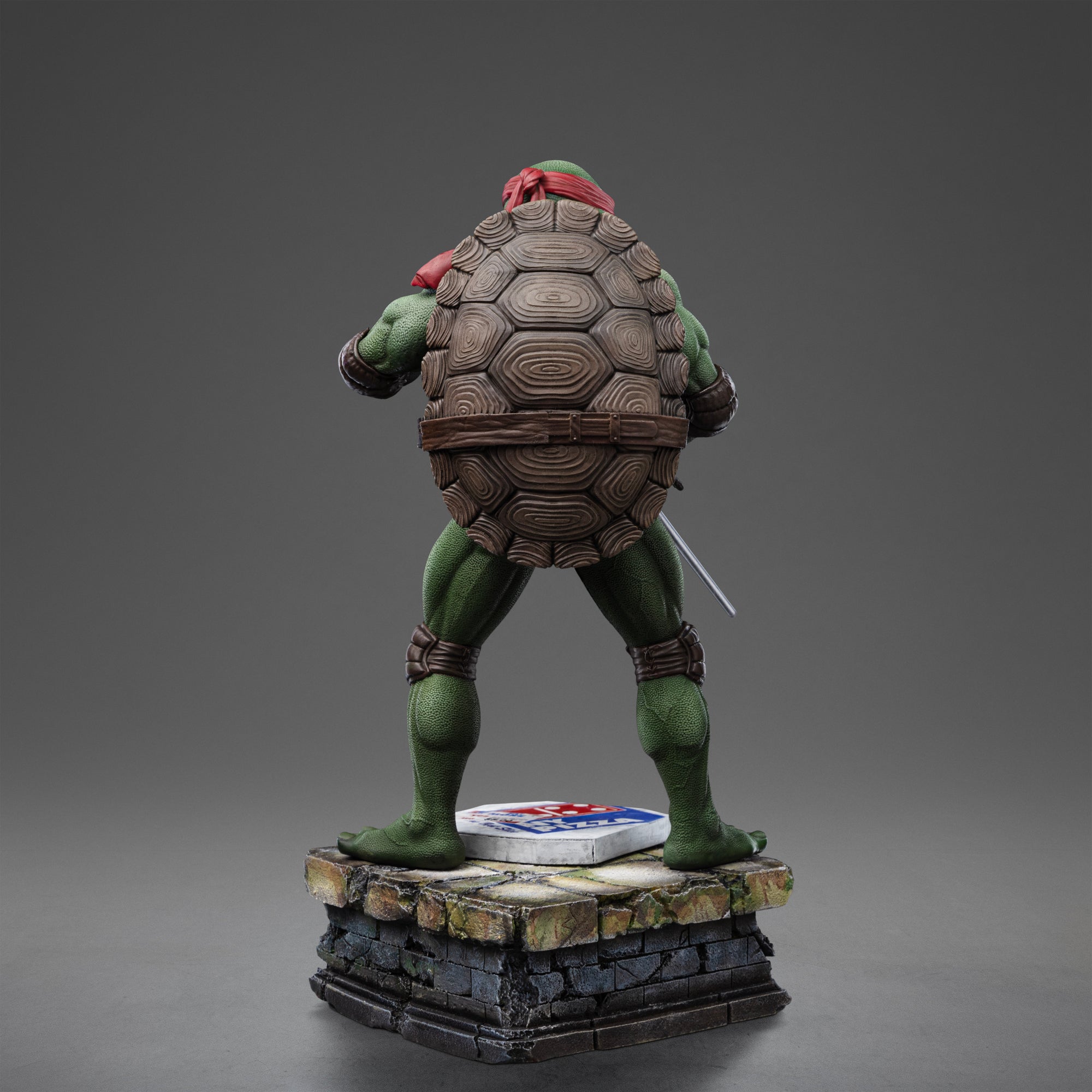 Full rear view of the Iron Studios TMNT 1990 Movie Raphael 1/10 scale polystone statue on a sewer pipe diorama base.