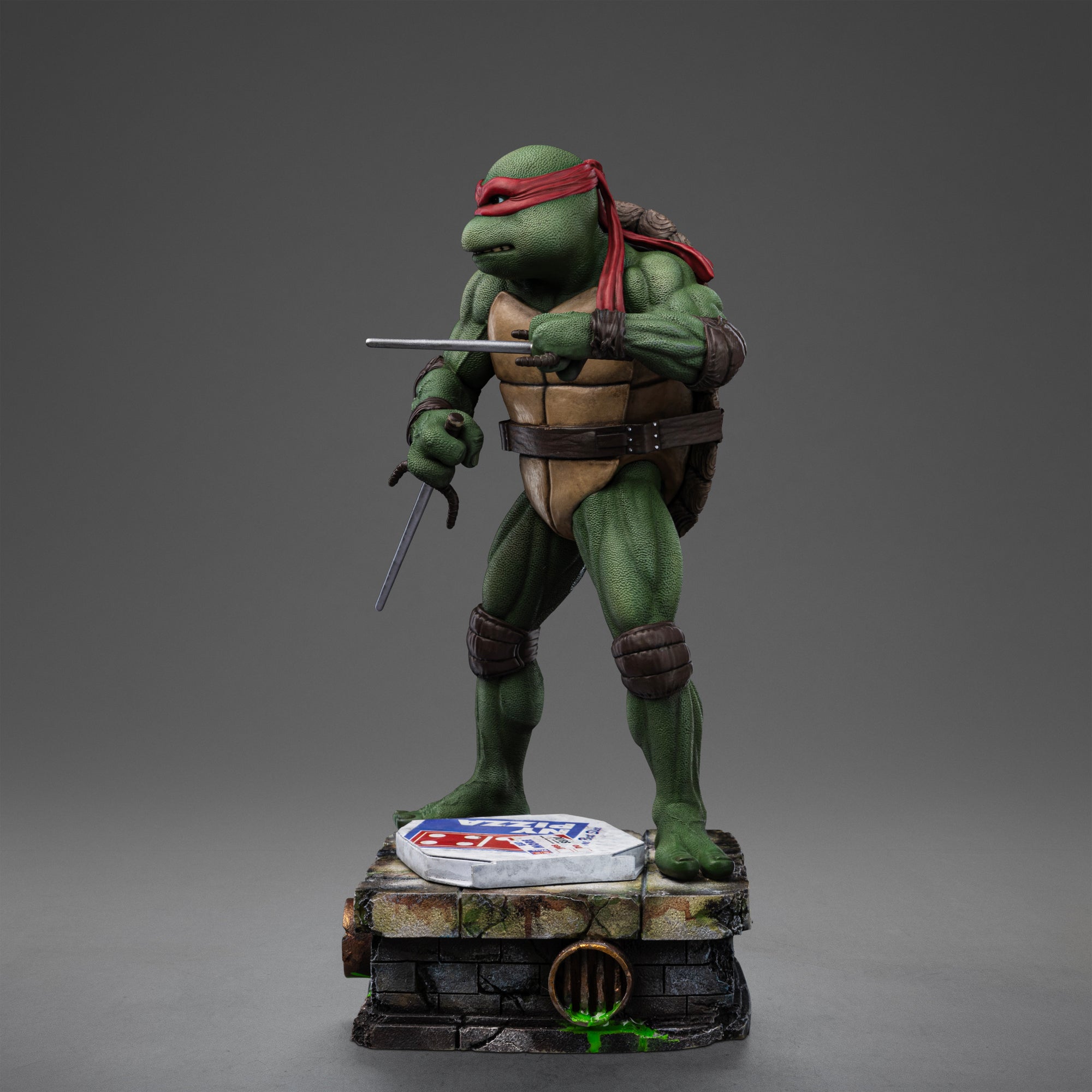 Left three-quarter perspective of the Iron Studios TMNT 1990 Raphael 1/10 statue posed with dual sai daggers ready for action.