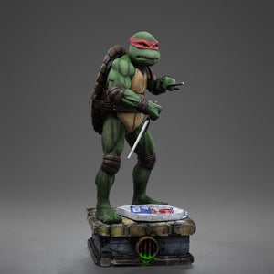 Right three-quarter studio view of the Iron Studios TMNT 1990 Raphael 1/10 statue wielding sai daggers on a sewer brick base.