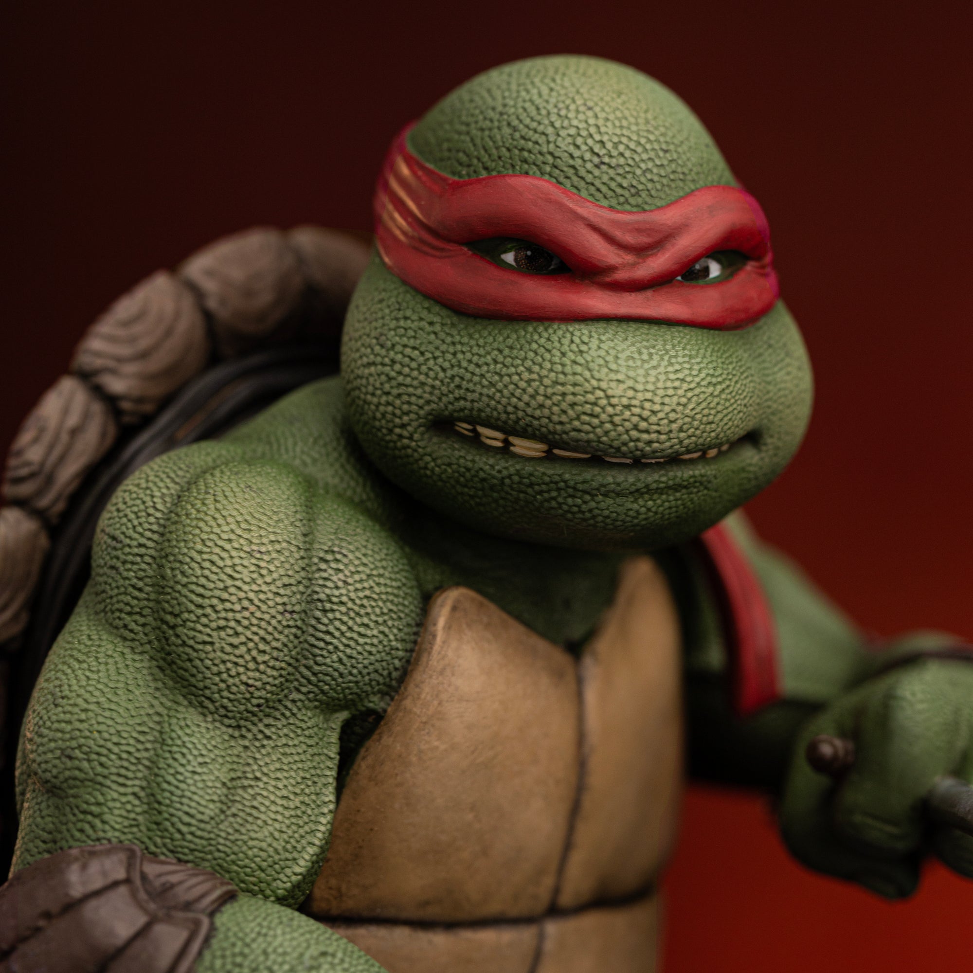 Close-up of Raphael's head sculpt with gritted teeth expression, red bandana, and detailed skin texture on the Iron Studios 1990 statue.