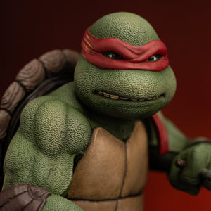 Close-up of Raphael's head sculpt with gritted teeth expression, red bandana, and detailed skin texture on the Iron Studios 1990 statue.