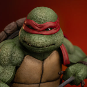 Frontal portrait close-up highlighting Raphael's textured green skin, brown eyes, and red eye mask on the Iron Studios TMNT figure.