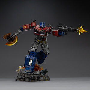 Low-angle perspective of the Iron Studios Optimus Prime 1/20 polystone statue advancing over a battle-damaged diorama base.