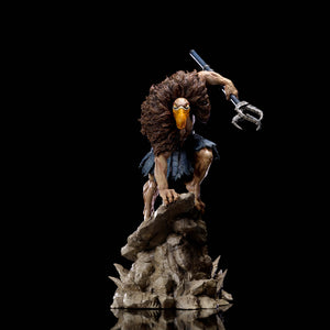 A slightly pulled back shot of the Vultureman statue, showing the full figure on the rocky base against a black background.