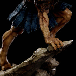 An extreme close-up on the Vultureman statue's arm and leg, showcasing the detailed muscular sculpt and the texture of the rock base.