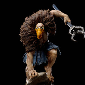 A close-up of the Vultureman statue, focusing on his yellow beak and the metallic, clawed end of his staff.
