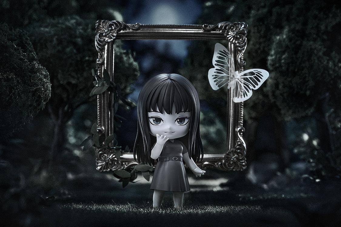 Cinematic lifestyle display of Tomie Nendoroid in a dark forest setting with a picture frame and paper butterfly.
