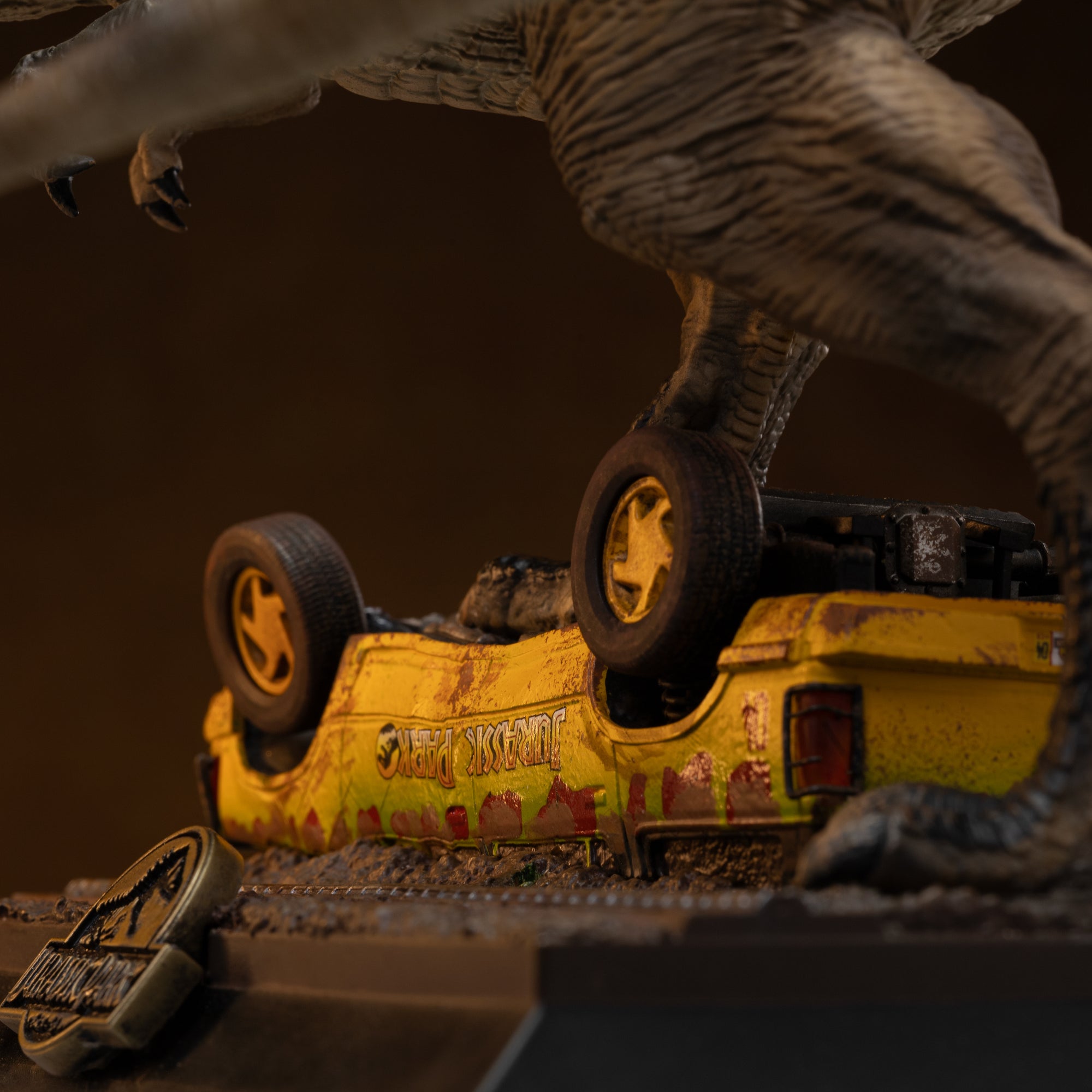 Close-up macro view of the overturned yellow and green Jurassic Park tour vehicle component, showing realistic mud splatters, weathering, and blood-like rust detailing under the T-Rex's weight.
