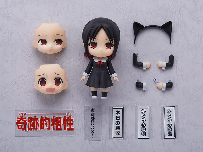 Flat lay knolling shot of the Kaguya-sama: Love is War Kaguya Shinomiya Nendoroid box contents, including interchangeable face plates, a cat ears headband, alternate arms, a flip phone, and various Japanese anime scene text plates.