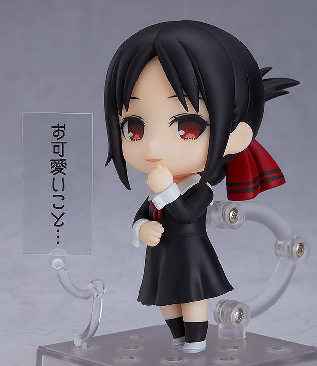 Kaguya Shinomiya Nendoroid figure displayed with her iconic condescending smirk face plate and a clear acrylic text plate containing Japanese dialogue translating to "How cute..." against a grey studio background.