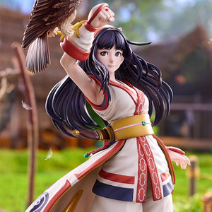 Close-up view of Nakoruru figure with floating feathers against a lush green outdoor village backdrop