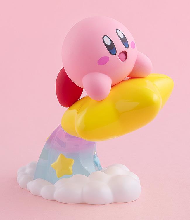 Studio front-facing profile of the pink Kirby figure riding a Warp Star, showcased against a solid pastel pink background.