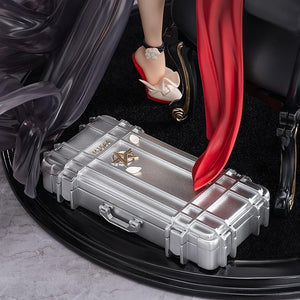 Detailed shot of the figure's base, showing the silver metallic gun case with the Knives Out logo and the base of the black velvet chair.