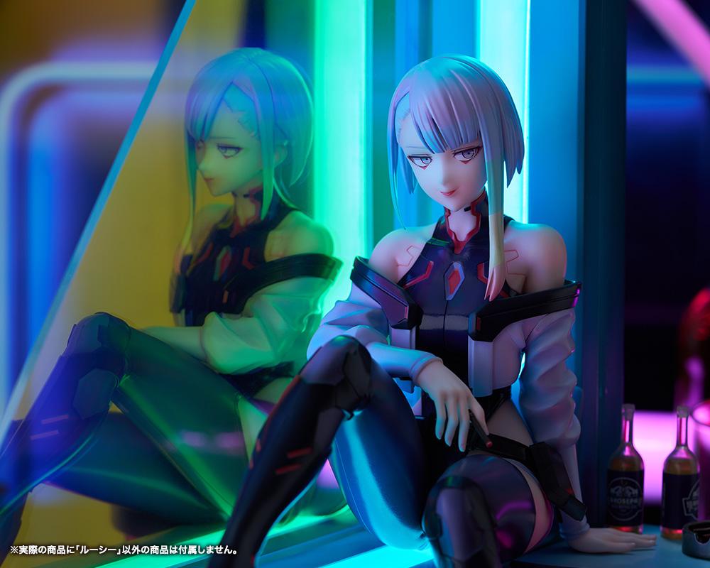 Close-up view of Lucy's face and rainbow hair illuminated by green and cyan neon lighting next to Aurora panel reflection.
