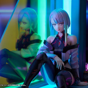 Close-up view of Lucy's face and rainbow hair illuminated by green and cyan neon lighting next to Aurora panel reflection.
