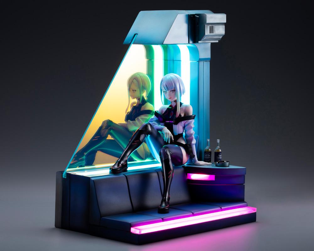 Lucy 1/7 scale figure and diorama base illuminated with vibrant pink and cyan LED neon lighting in dark setting.