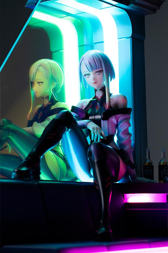 Low-angle close-up of Lucy figure under atmospheric cyan and green neon LED lighting.