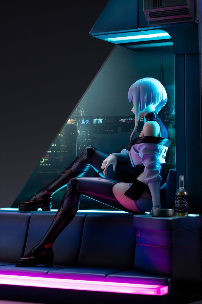 Side perspective of Lucy seated beside the glowing Night City window panel under neon room lights.