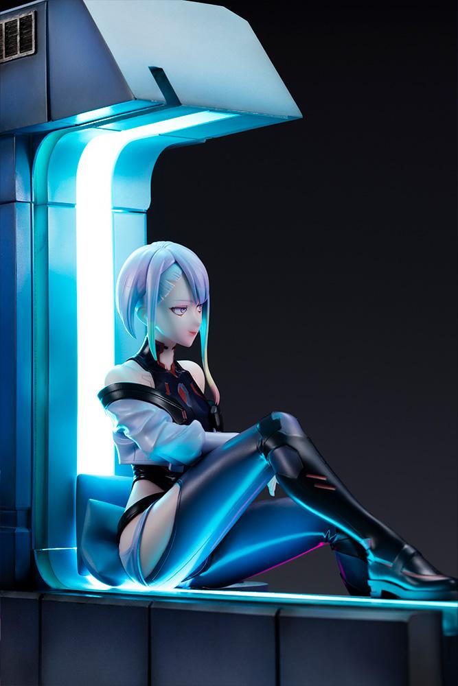 Right profile angle of Lucy resting on window couch illuminated by vertical cyan neon LED strip.