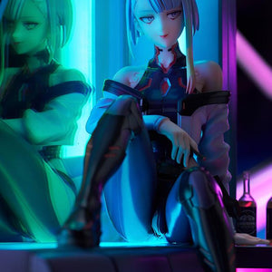 Vertical low-angle portrait of Lucy figure seated on LED sofa base under intense cyan and magenta lighting.