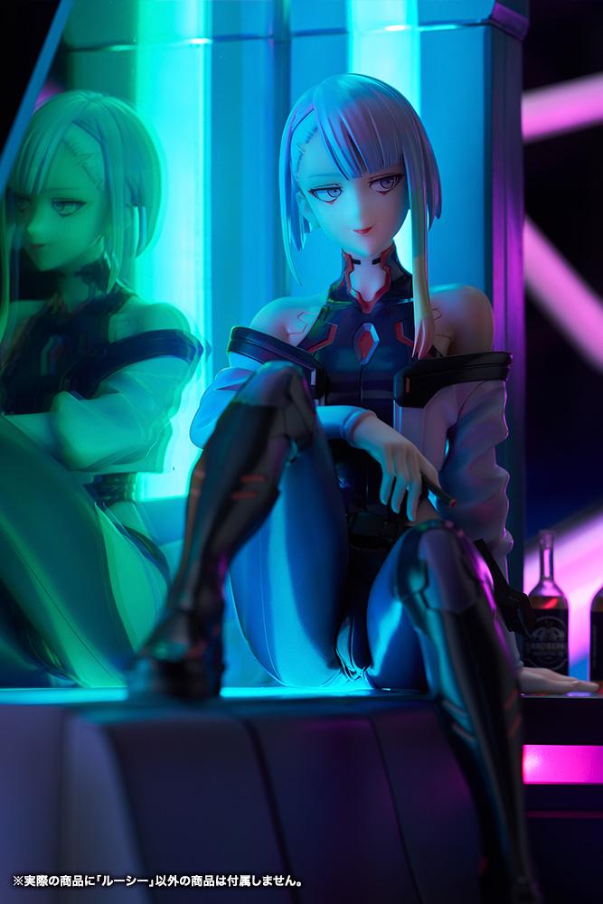 Vertical low-angle portrait of Lucy figure seated on LED sofa base under intense cyan and magenta lighting.