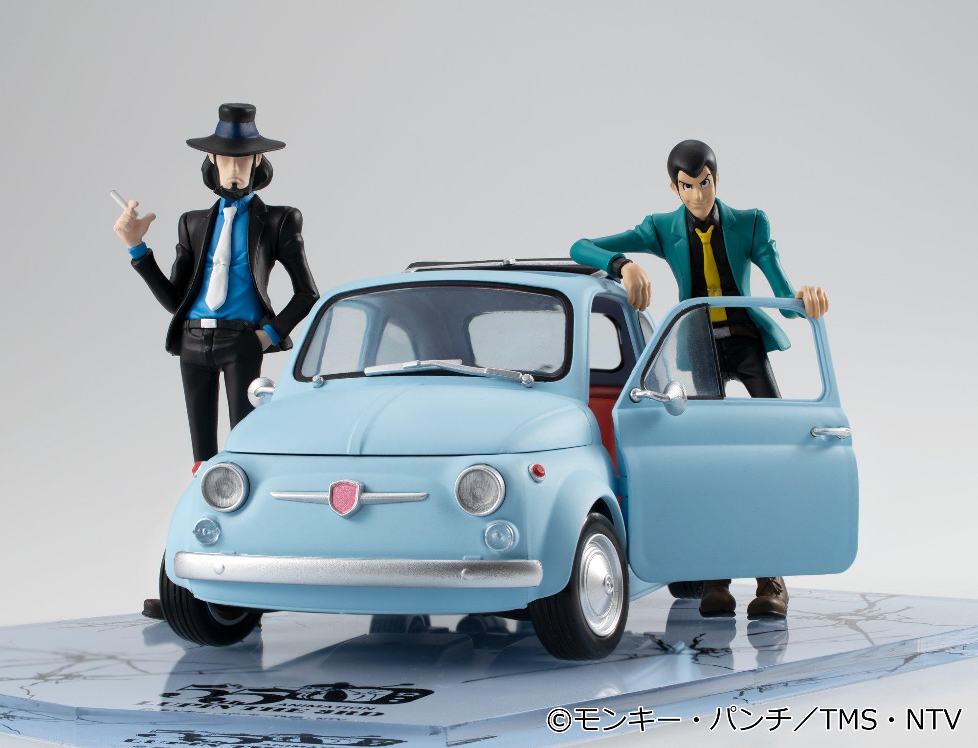 Close-up front view of Lupin in green jacket leaning on the ice blue vehicle door.