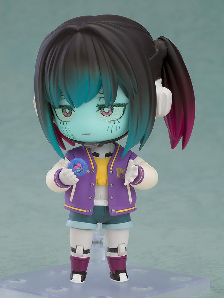 Makina Nendoroid figure holding a small blue badge accessory with colorful graphics.