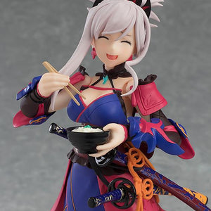 A close-up of the Miyamoto Musashi figma figure, featuring her happy expression as she holds a bowl of udon with chopsticks.