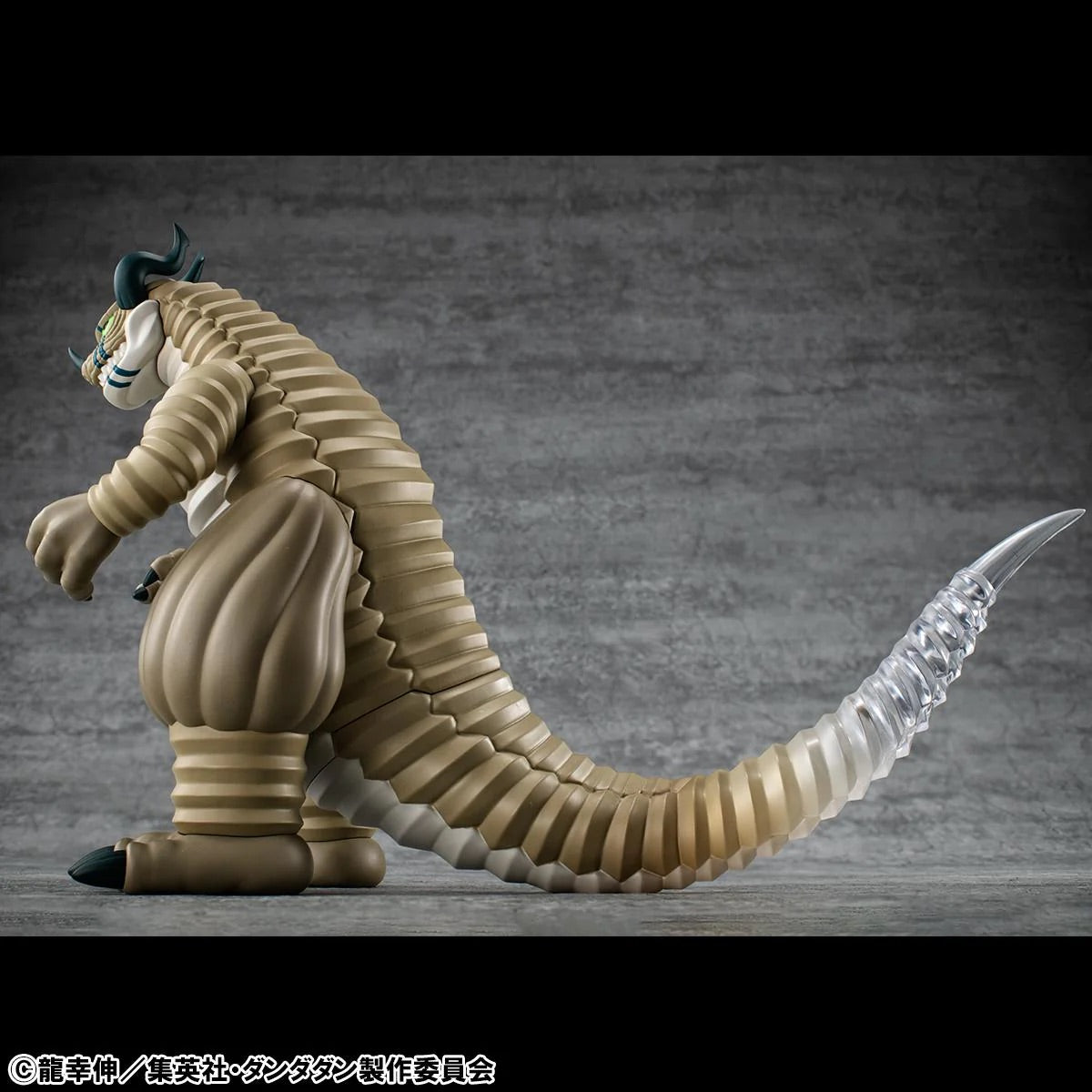 A detailed side-back view of the Transparent Kaiju figure, highlighting the long segmented tail and the gradient effect of the clear material.