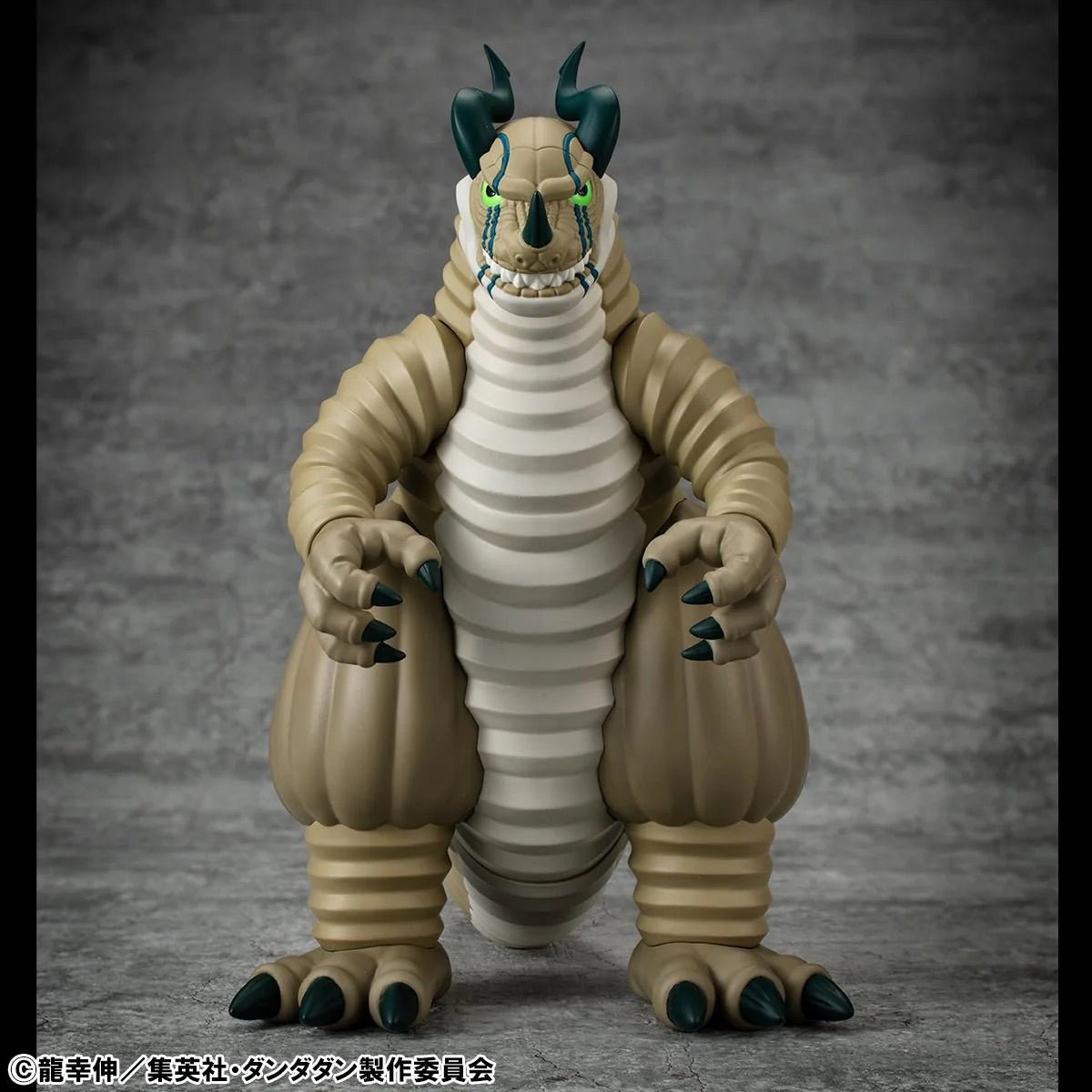 Frontal view of the Transparent Kaiju figure, emphasizing the beige segmented body, green glowing eyes, and small horns.