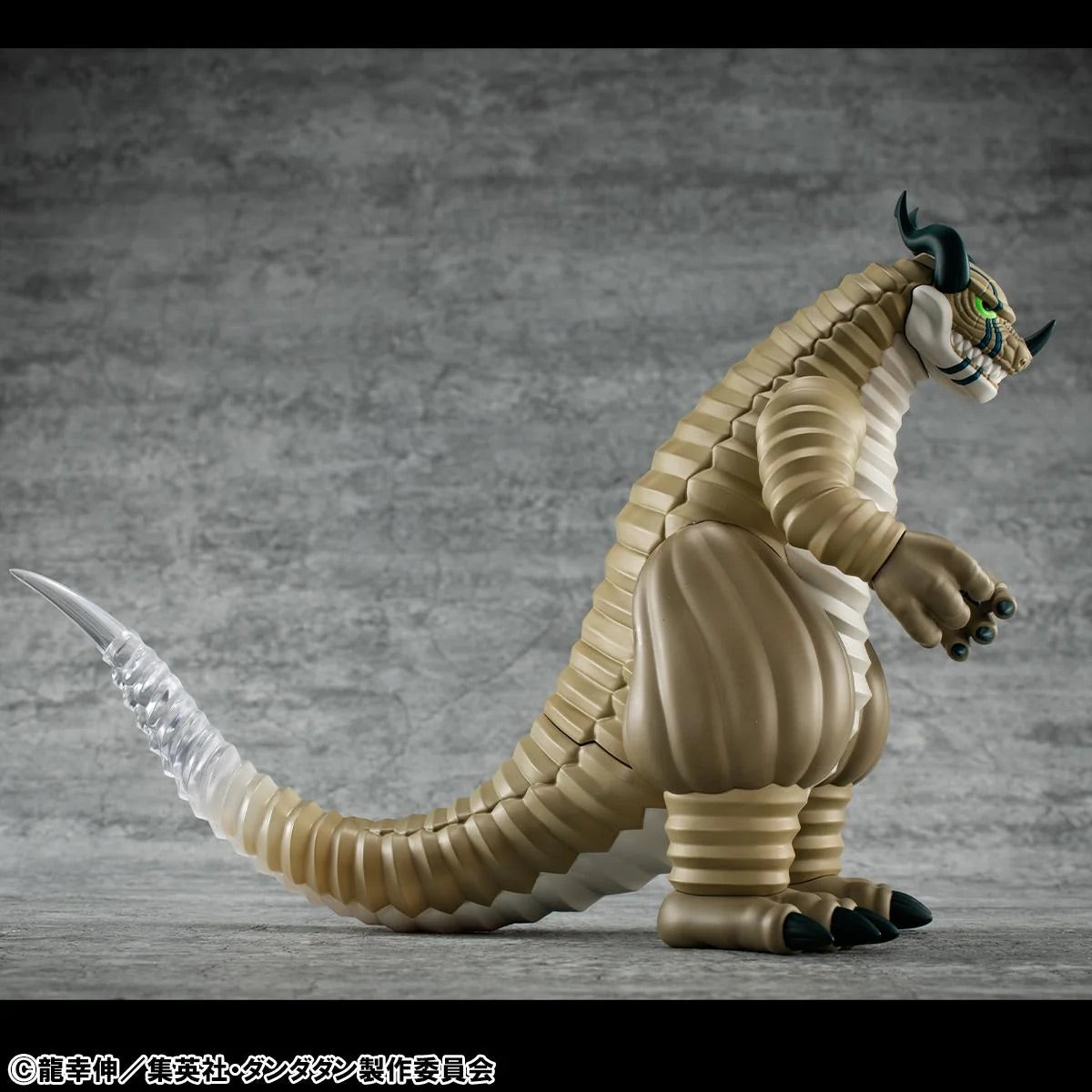 Side profile of the Transparent Kaiju figure, showing its long, segmented body and the translucent, clear tip of its tail representing its invisibility power.