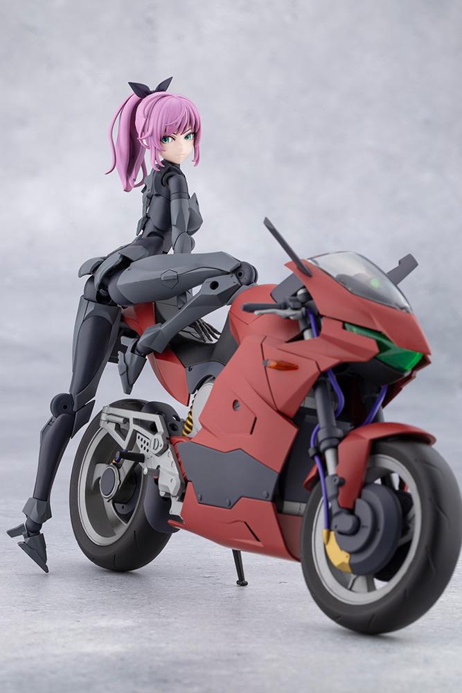 Dynamic low rear angle of Emulator straddling the parked red sports motorcycle looking back over her shoulder.