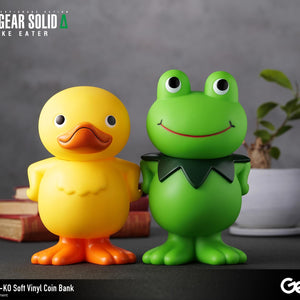 GA-KO yellow duck and Kerotan green frog soft vinyl coin banks displayed together on a decorated desk surface.