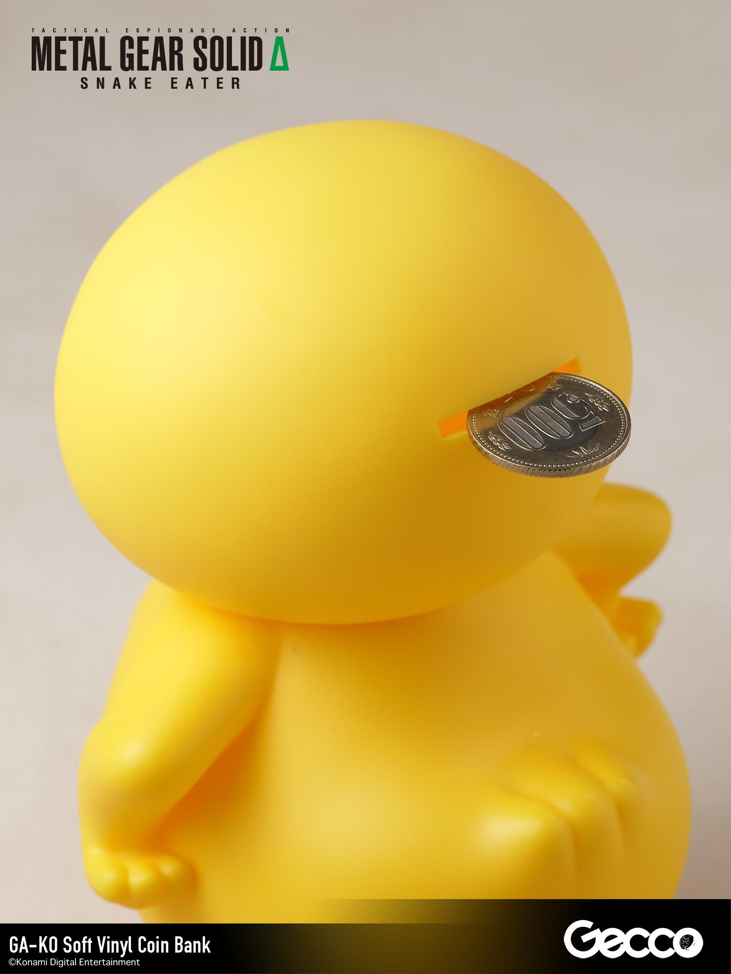 Close-up shot of a coin being inserted into the slot on the back of the GA-KO duck vinyl coin bank.