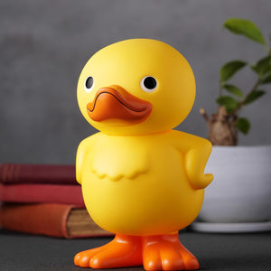 Three-quarter left angle shot of the GA-KO duck vinyl bank on a lifestyle desk setup.