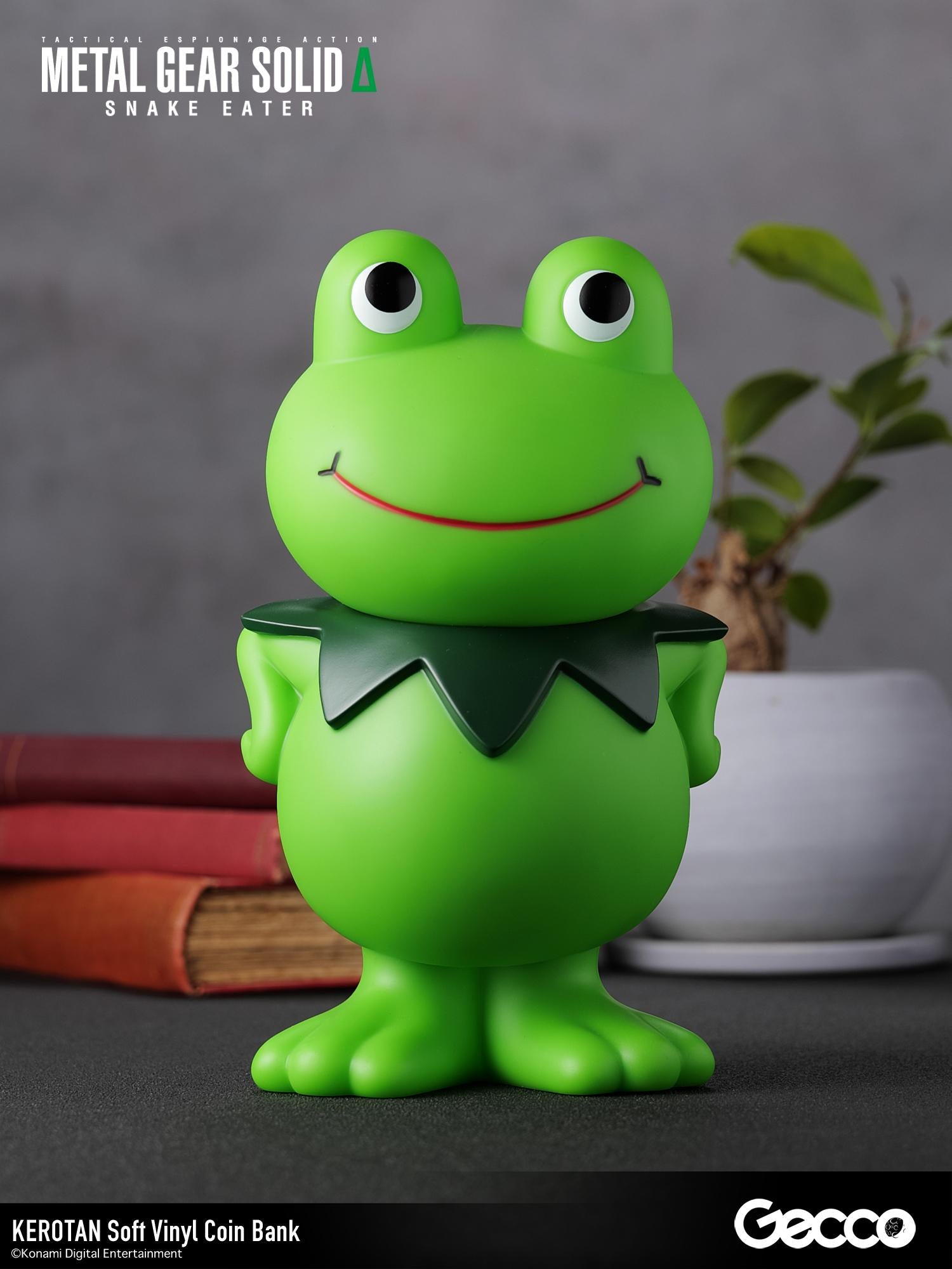 Front view of the Kerotan soft vinyl coin bank arranged on a desk display with books and houseplant.