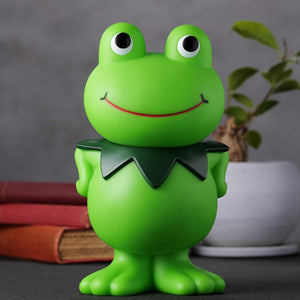 Front view of the Kerotan soft vinyl coin bank arranged on a desk display with books and houseplant.