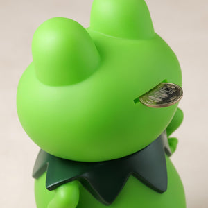 Close-up view of a coin being inserted into the slot on the back of the Kerotan vinyl coin bank.