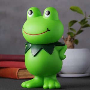 Three-quarter right angle shot of the Kerotan frog vinyl bank on a lifestyle desk setup.