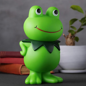 Three-quarter left angle shot of the Kerotan soft vinyl coin bank sitting on a desk alongside decor.