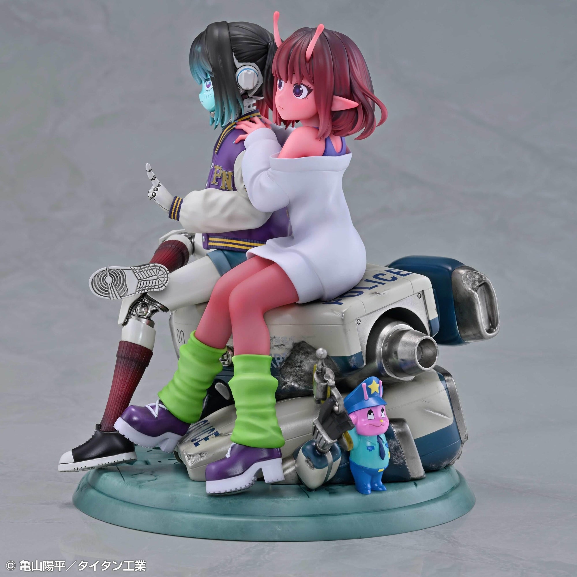 Side profile view of Makina leaning against Chiharu while sitting atop a retro futuristic police car base.