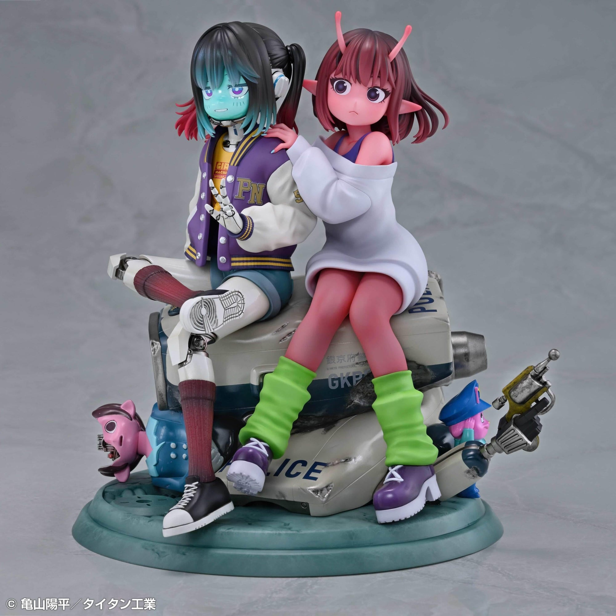 Front angle view of the Chiharu and Makina figure display showing their vibrant outfits, leg warmers, and themed diorama base.