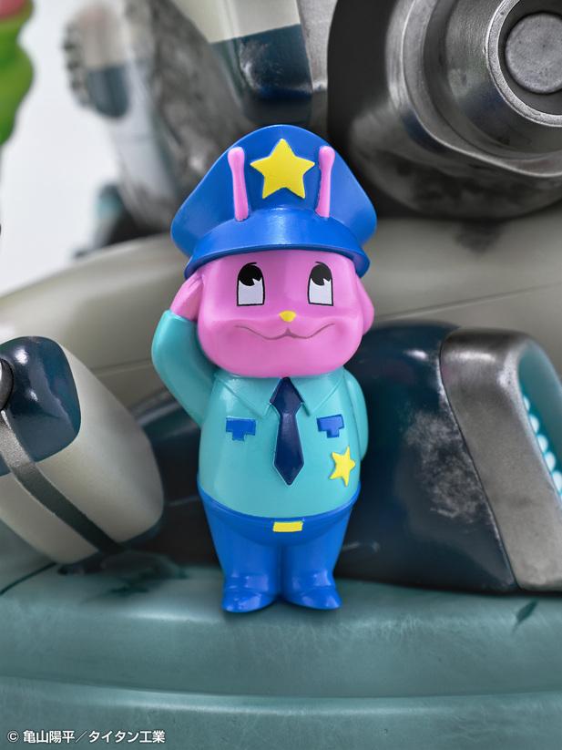 Close-up view of the small pink alien police officer mascot figure saluting on the diorama base.