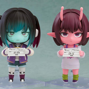 Comparison shot featuring Makina and Chiharu Nendoroids side-by-side holding their respective mugshot papers.