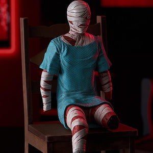 Angled view of the Mouthwashing Curly Swacchao! sitting figure perched on a small wooden chair with dramatic red ambient background lighting.
