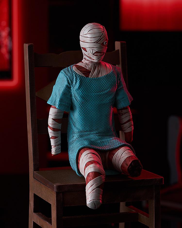 Angled view of the Mouthwashing Curly Swacchao! sitting figure perched on a small wooden chair with dramatic red ambient background lighting.