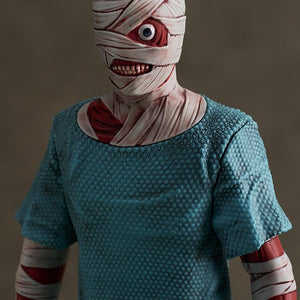 Detailed close-up portrait of Curly's bandaged head, exposed eye, smiling mouth, and textured blue hospital gown from the Mouthwashing video game figure.